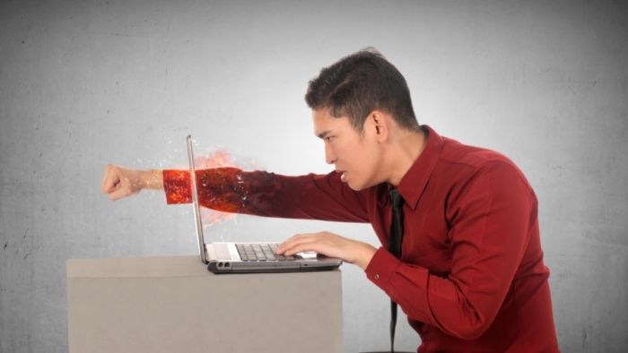 man punches laptop